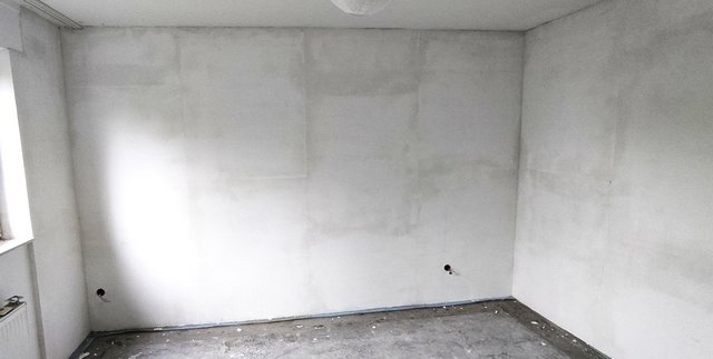 Helle Wand mit unregelmäßigen Flecken in leerem Raum.