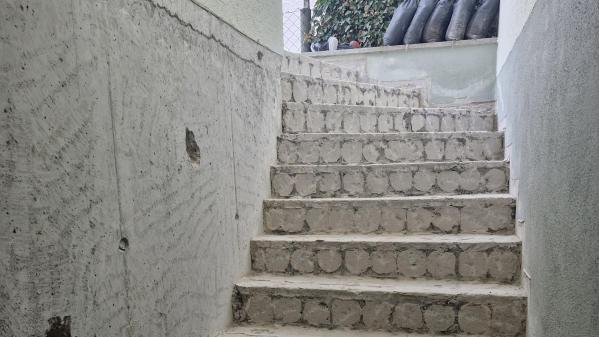 Treppenaufgang mit unfertigen Betonstufen und gefliesten Stufen im unteren Bereich