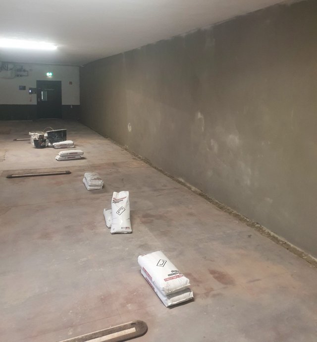 Langer Kellerraum mit frisch geglätteter grauer Wand und Säcken auf dem Boden