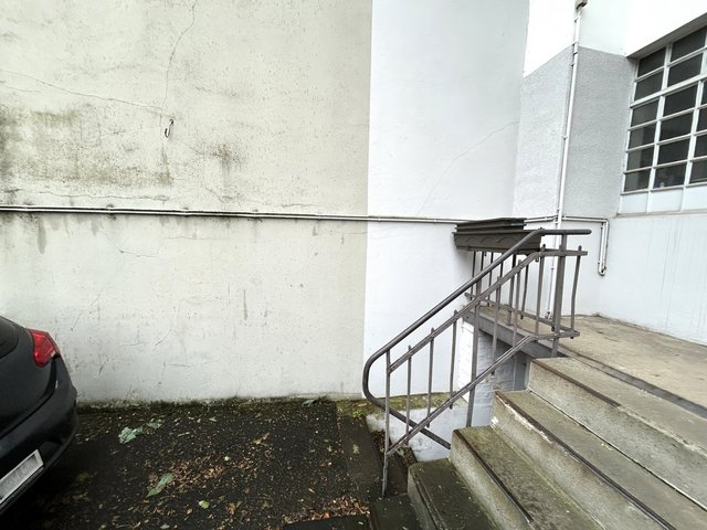 Rissige Fassade mit dunklen Feuchtigkeitsspuren neben Außentreppe