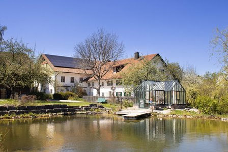 Landhaus mit Solardach, Gewaechshaus und Holzsteg am Teich