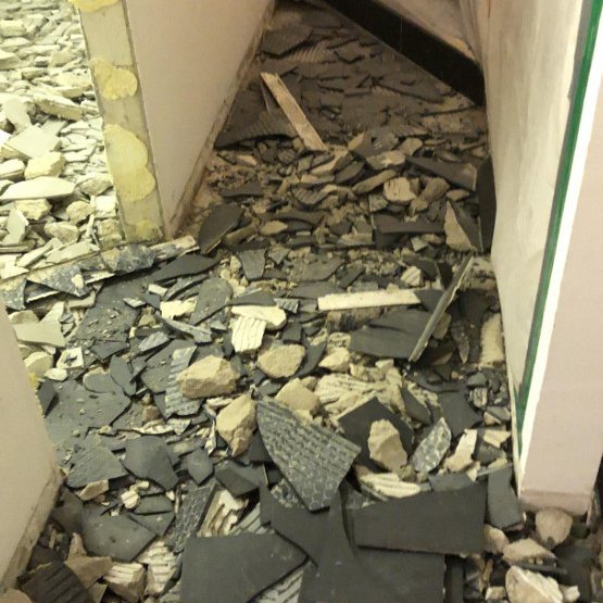 Flur mit herausgerissenen Bodenfliesen und Bauschutt, Blick zur Treppe
