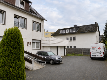 ISOTEC Transporter steht auf Hof vor Wohnhaus mit Balkon und Garage.