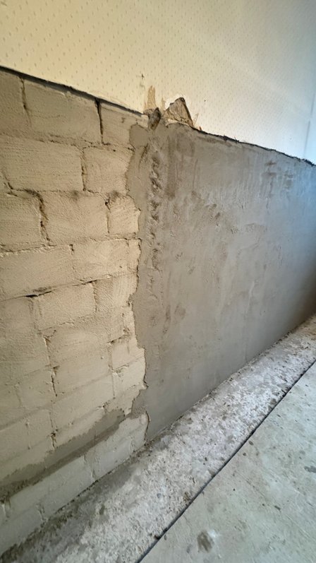 Teilweise verputzte Mauer aus hellen Steinen im Innenraum