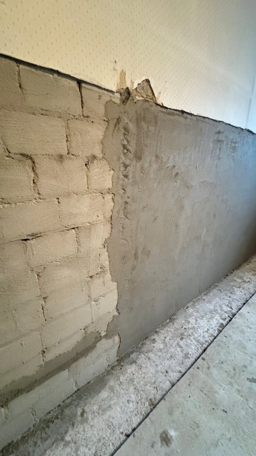 Teilweise verputzte Mauer aus hellen Steinen im Innenraum