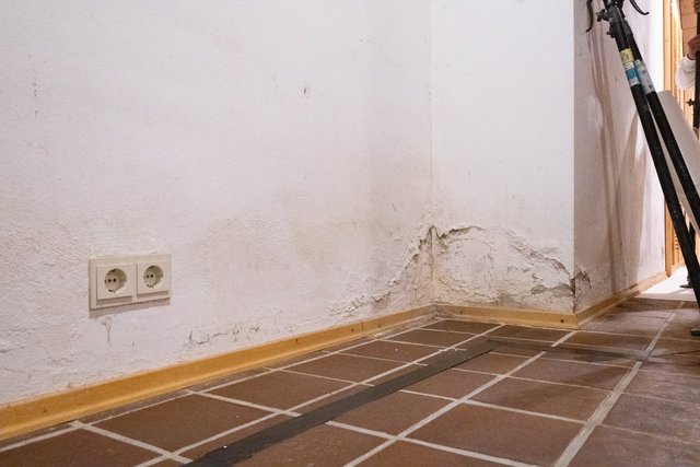 Abgeplatzte Wandfläche mit Feuchtigkeitsspuren an einer Zimmerecke