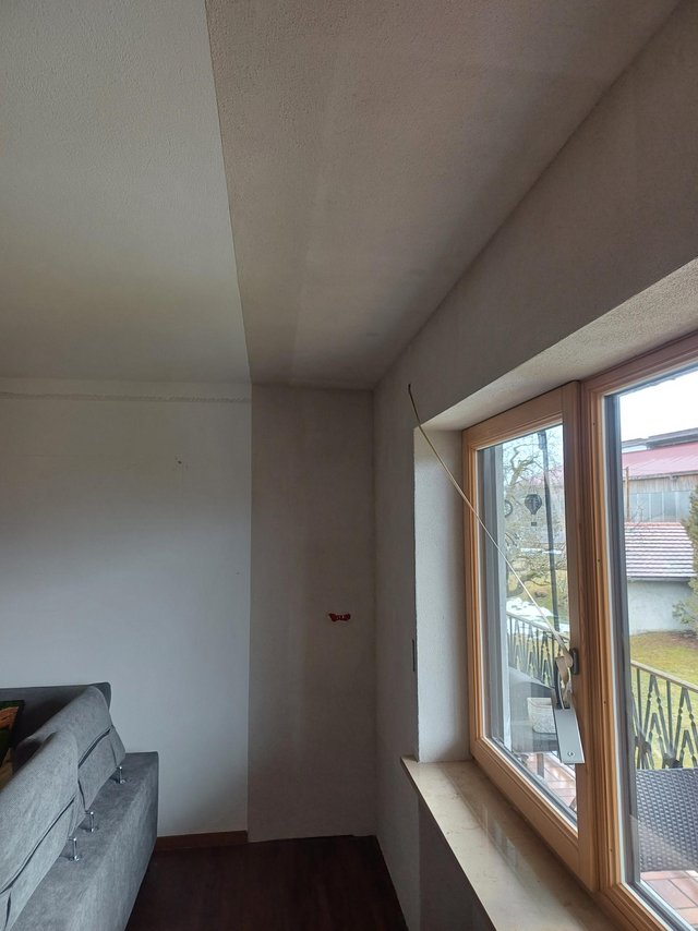 Decke mit dunklerer Fläche über Fenster und Wandbereich