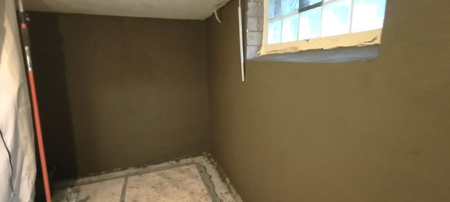 Frisch beschichtete Kellerwand unter Fenster