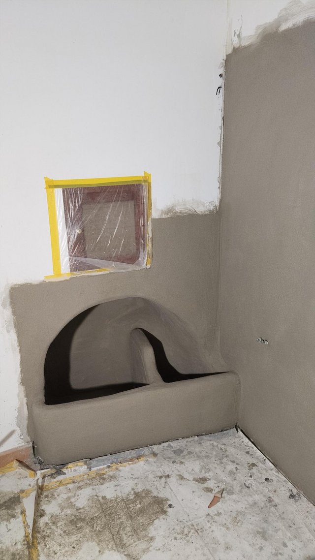 Graue Masse an Wandnische aufgetragen, Fenster mit Folie und Klebeband abgeklebt.