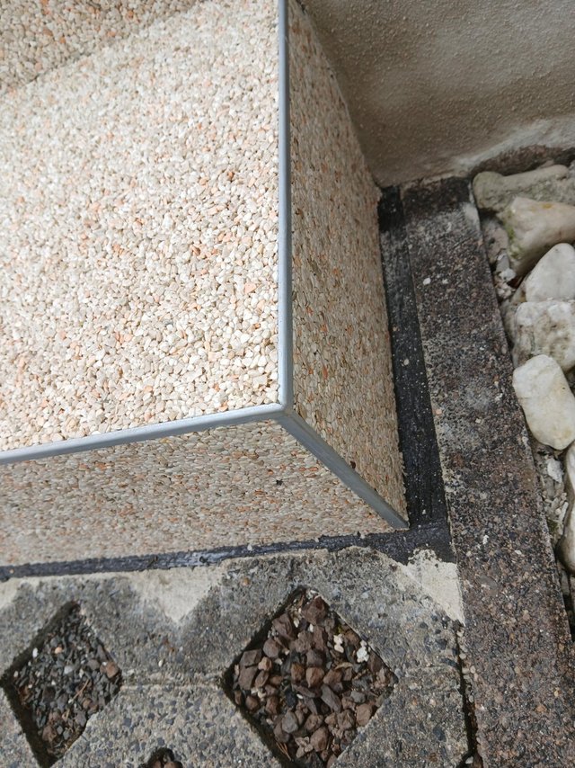 Schwarze Fuge an Gebäudesockel mit Kieselsteinverkleidung, Nahaufnahme