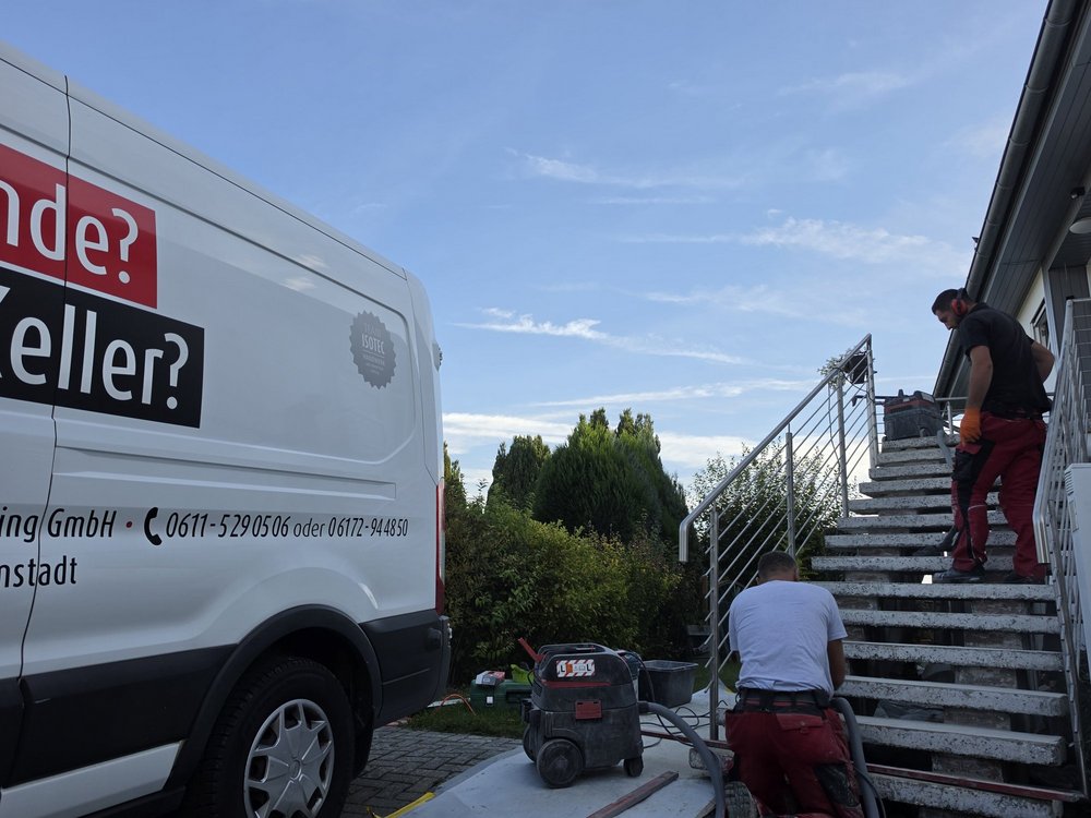 ISOTEC Mitarbeiter bearbeitet graue Betontreppe, daneben steht Industriesauger