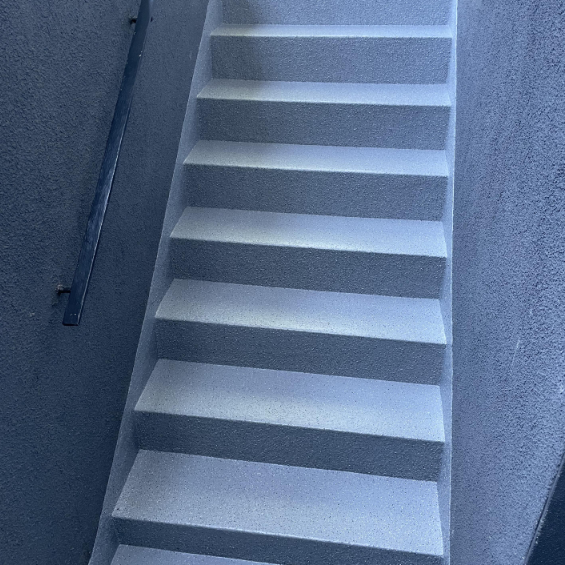 Hellgraue Betontreppe mit rutschfester Beschichtung im engen Treppenhaus, Blick nach oben