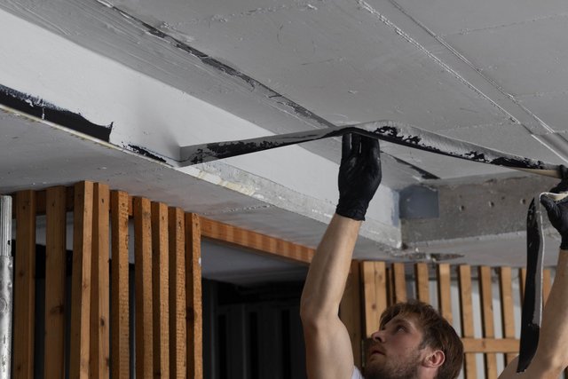 Person zieht helle Platte von einer Betondecke ab, Nahaufnahme.