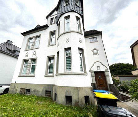 Weißes Wohnhaus mit Erkerturm und dekorativen Fassadenelementen