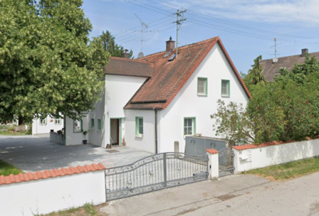 Weißes Einfamilienhaus mit rotem Satteldach, Garten und Metalltor