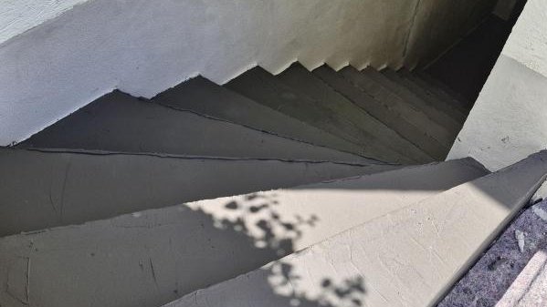 Graue Treppe mit frisch beschichteten Stufen, Blick nach unten ins Treppenhaus