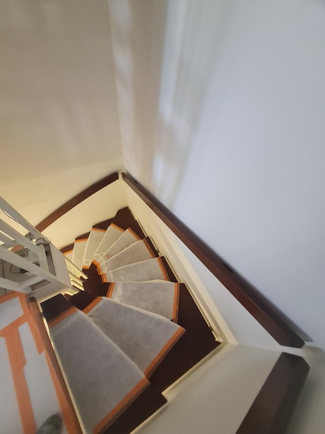 Blick von oben auf Wendeltreppe mit dunklen Stufen und grauen Stufenauflagen.
