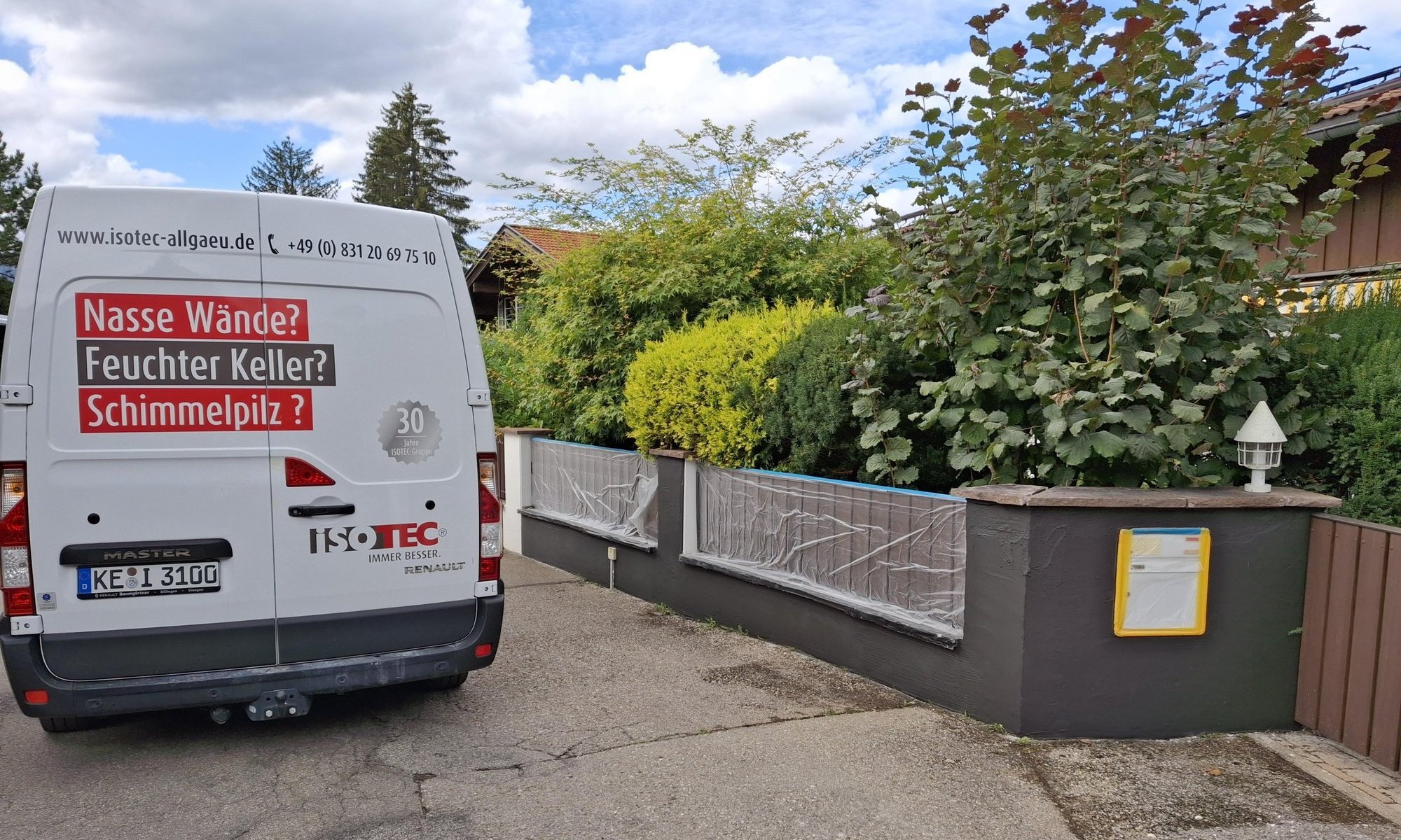 ISOTEC Transporter steht neben abgeklebter Grundstücksmauer.