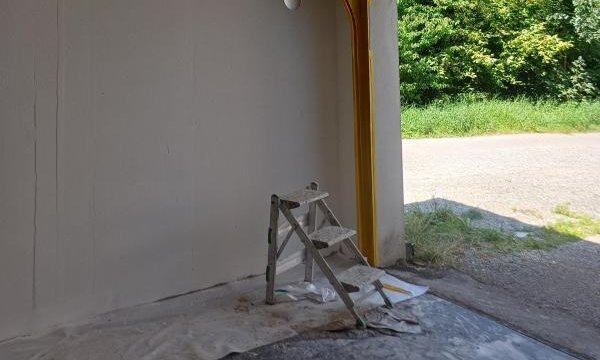 Abgedeckte Decke mit Folie und Klebeband in leerem Raum, Leiter am Boden.