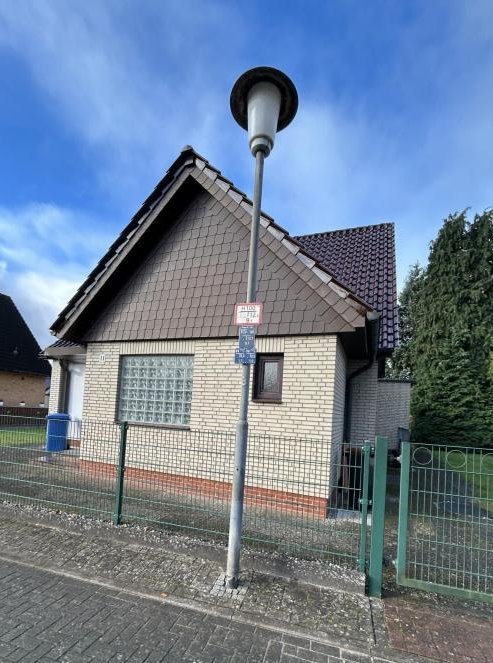 Einfamilienhaus mit heller Klinkerfassade, Vorgartenzaun und Straßenlaterne vor dem Gebäude