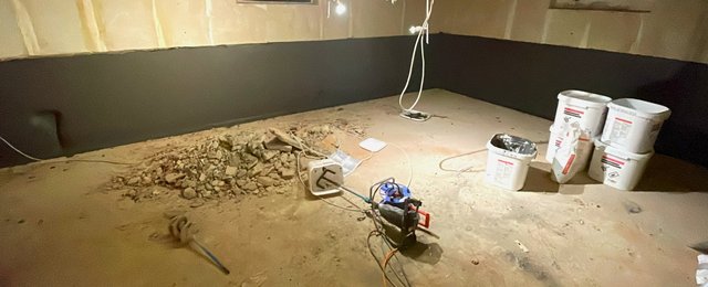 Bauschutt liegt neben weißen Eimern und Elektrowerkzeug auf staubigem Boden
