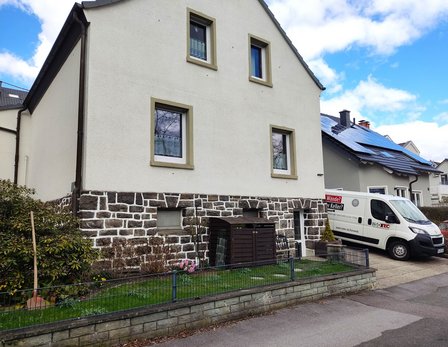 Wohnhaus mit Naturstein-Sockel und ISOTEC Fahrzeug in der Einfahrt