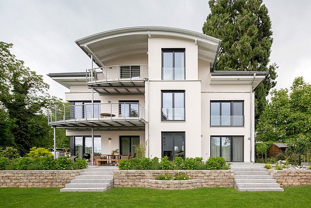 Modernes Wohnhaus mit breiten Balkonen und gepflegtem Garten