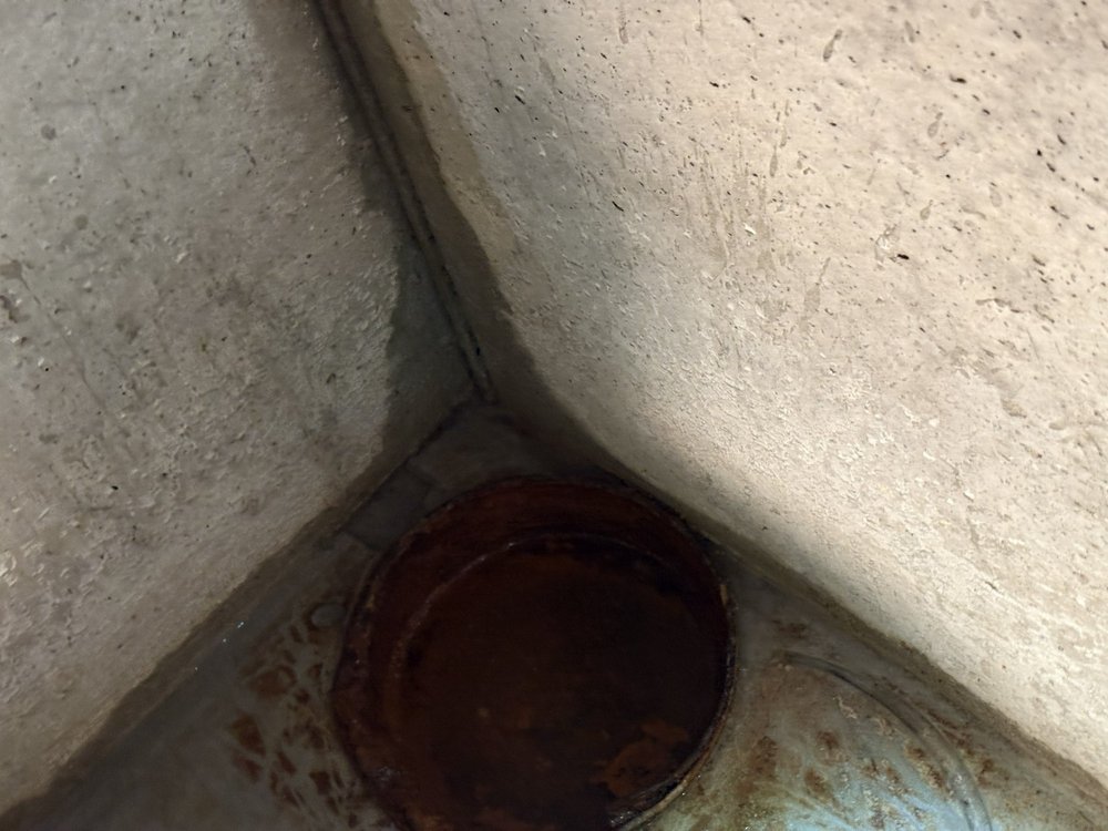 Feuchte Betonecke mit rostigem Bodenablauf, Nahaufnahme