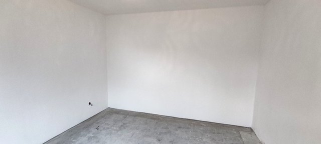 Leerer Raum mit weißen Wänden und rohem Boden