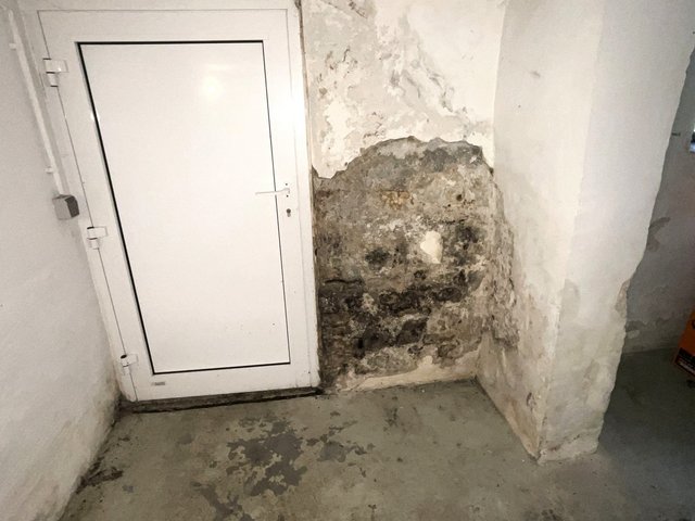 Abgeplatzte Wand mit freiliegendem Mauerwerk neben Tür