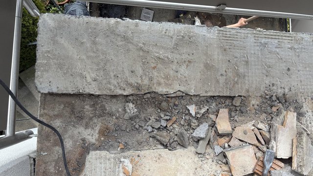 Abgebrochene Betonkante mit Bauschutt und Fliesenresten, Draufsicht