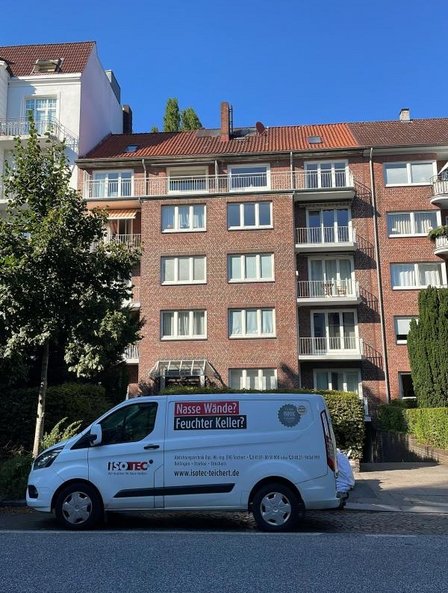 ISOTEC Transporter vor Mehrfamilienhaus mit roter Backsteinfassade und Balkonen