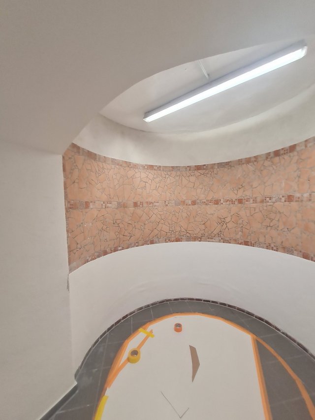 Gewölbter Flur mit Mosaikband, Deckenleuchte und abgeklebt geschütztem Boden