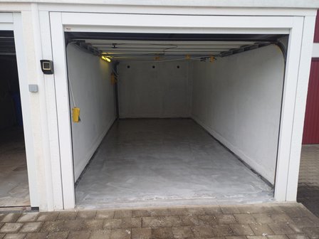 Leere Garage mit grauem Boden und weißen Wänden, Garagentor geöffnet