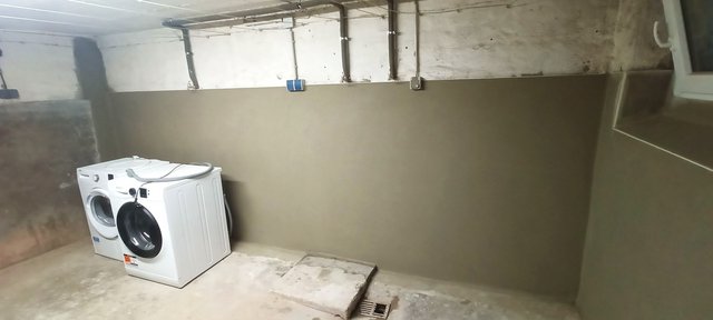 Waschkeller mit Waschmaschine, gestrichener Kellerwand und Bodenablauf
