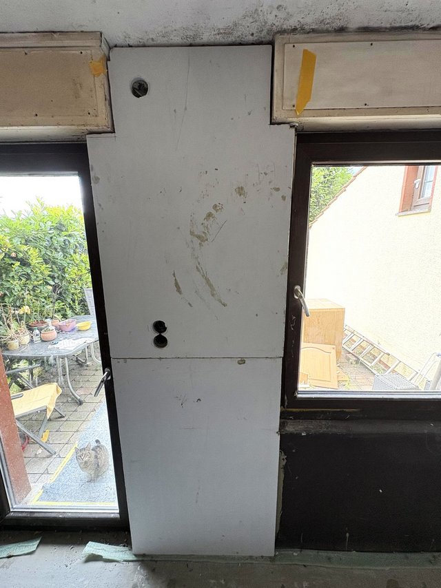Helle Platte zwischen Fenstern mit Bohrlöchern, darüber schwarze Flecken am Deckenrand.