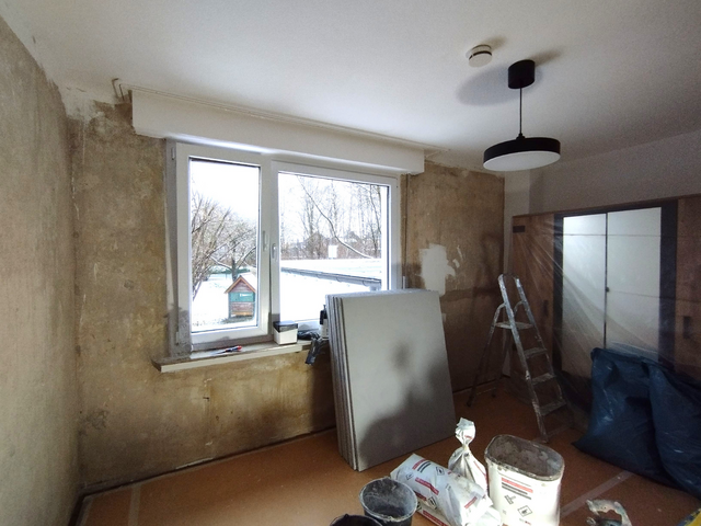 Renovierungsraum mit abgekratzten Wänden, Platten und Leiter