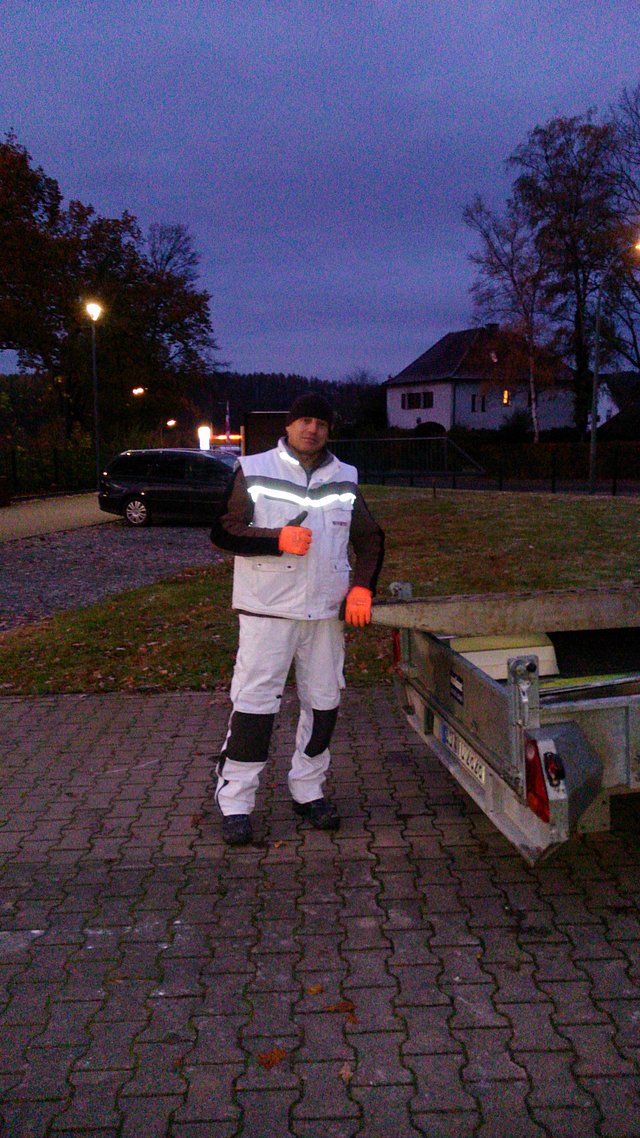 Helfer Igor vom Team Isotec-Pläsken morgens im Dunkeln beim Abladen des Schutts vom Vortag und beim Aufladen der benötigten Materialien für z.B. Außenabdichtung Baustelle an diesem Tag