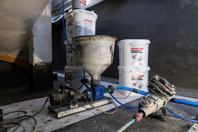 ISOTEC Eimer und Mischtrichter an Pumpe mit Schläuchen auf Baustellenboden
