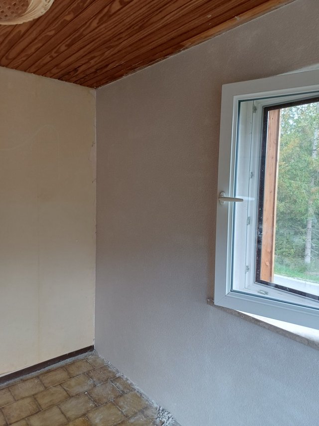 Helle strukturierte Zimmerwand neben geöffnetem Fenster und Holzdecke