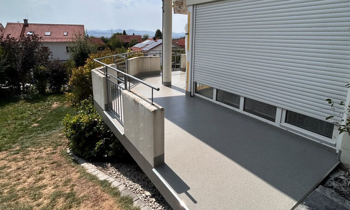 Beton-Balkon mit Metallgeländer an Hausfassade, Blick auf Garten und Dächer