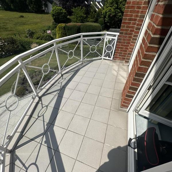 Gefliester Balkon mit weißem Metallgeländer und Blick auf Garten
