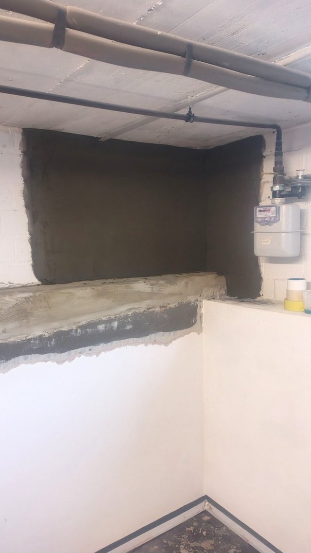 Kellerwand mit aufgetragener schwarzer Masse, Rohre an der Decke