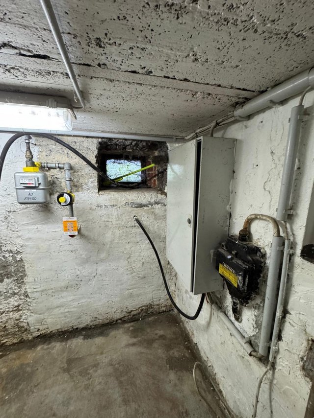 Schimmelspuren an Kellerdecke und Wand neben Leitungen und Zählerkasten