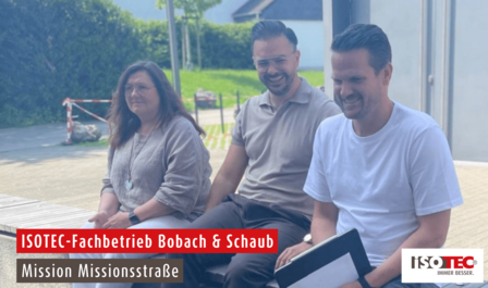 ISOTEC Mitarbeiter sitzen im Freien und lächeln, Besprechungsszene mit Klemmbrett.