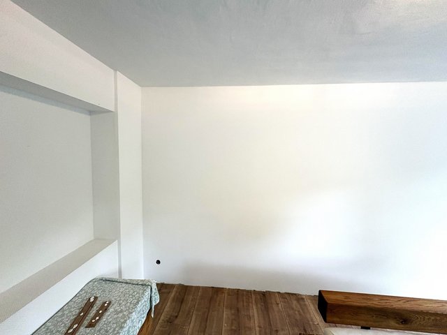 Leerer Raum mit weißen Regalbrettern, weißer Decke und Holzboden