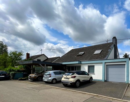 Wohnhaus mit Carport und mehreren geparkten Autos.