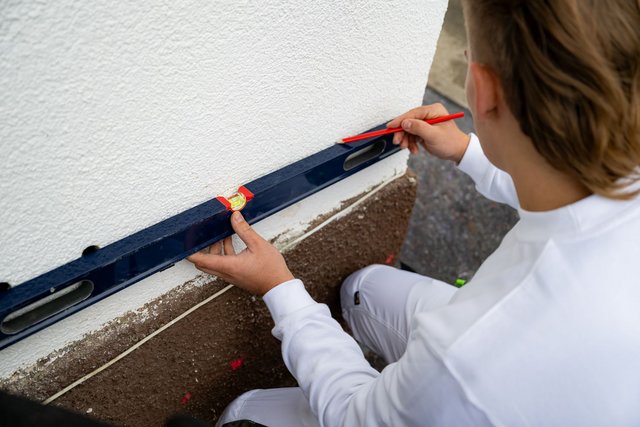Mit einer Wasserwaage werden die Markierungen für die Bohrlochkanäle angezeichnet