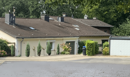 Gelbes Wohnhaus mit braunem Dach und gepflegtem Vorgarten