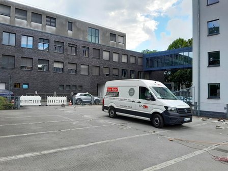 ISOTEC Transporter auf Parkplatz vor modernem Gebäude mit Glasbrücke
